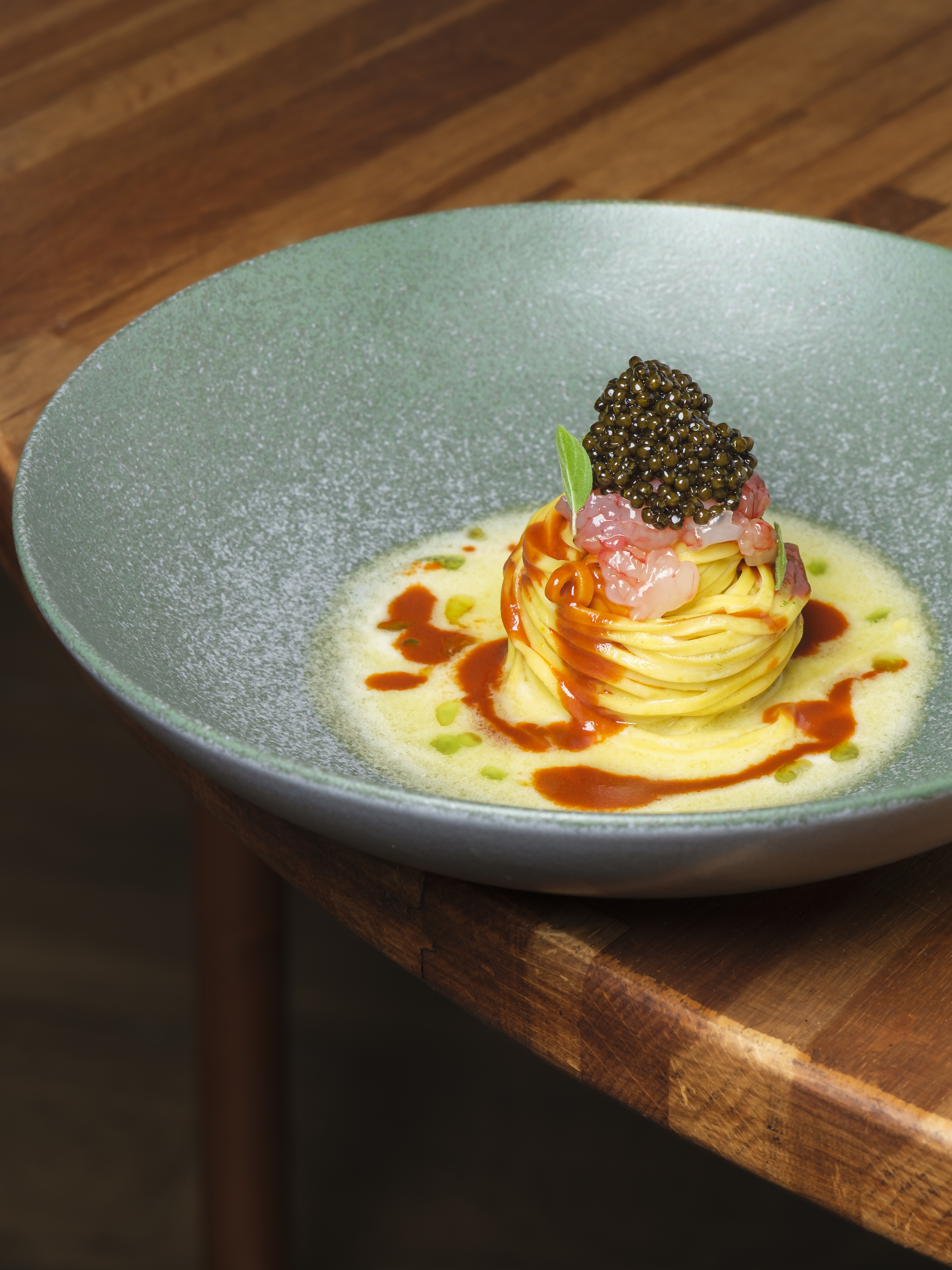 Tagliolini nested on green stoneware, crowned with gambero rosso and oscietra caviar