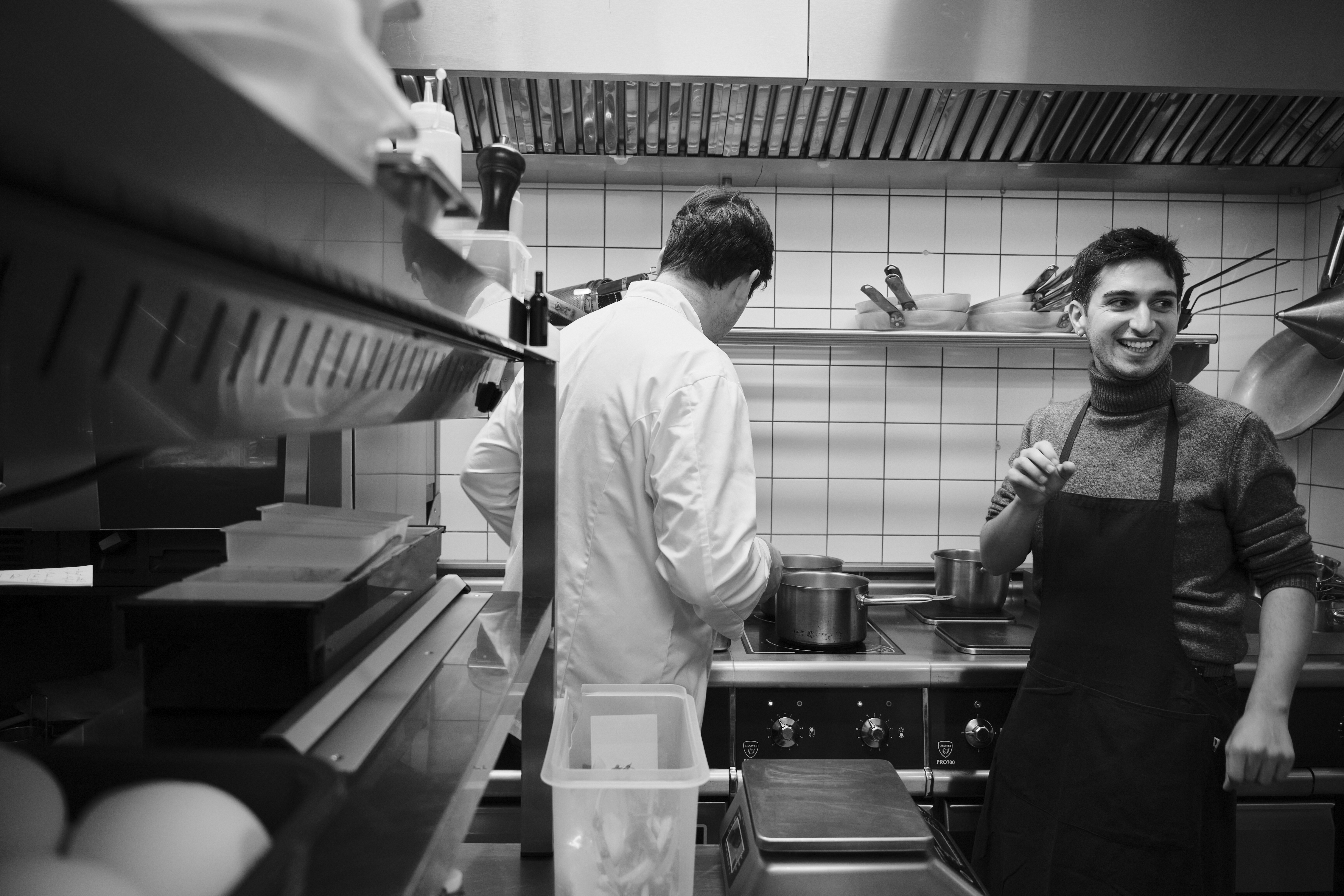 Two cooks at the stove during an evening service, in black and white